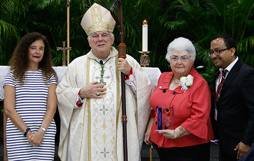 Accompanied by Superintendent of Schools Kim Pryzbylski, left, and Office of Catechesis Director Peter Ductram, Archbishop Thomas Wenski gives a 2016 Catechetical Leadership Award to Leyla Mazpule, director of religious education at Sts. Peter and Paul Parish in Miami.