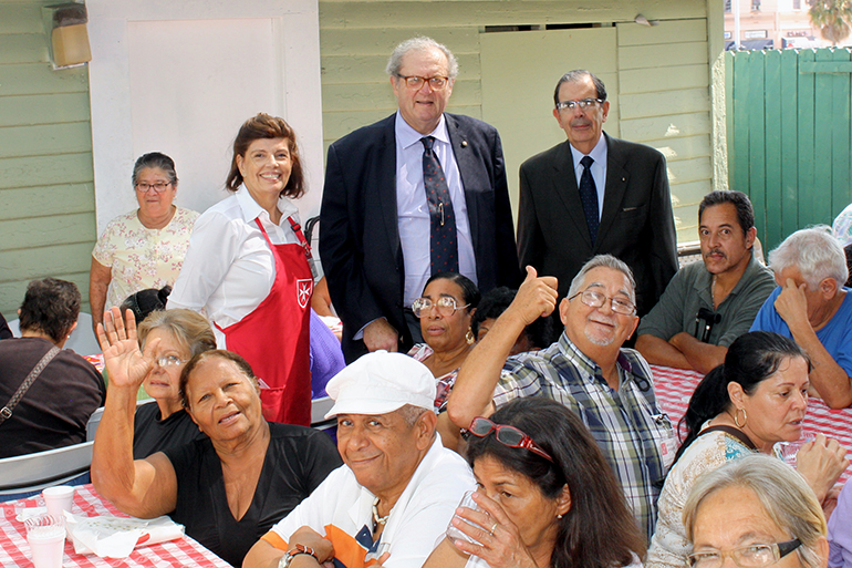 Fra' Matthew Festing, centro, se ve aqu&iacute; con Juan Jos&eacute; Calvo, presidente de la Asociaci&oacute;n Cubana de la Orden de Malta, y su esposa, Valentina, en medio de los pobres y ancianos de la Peque&ntilde;a Habana que acuden diariamente a la Casa de Malta en la parroquia San Juan Bosco, uno de los proyectos de la Asociaci&oacute;n Cubana en Miami.