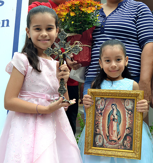 Elizabeth, left, and Jennifer show the gifts from Archbishop Wenski: an ornate crucifix and a picture of Our Lady of Guadalupe.
