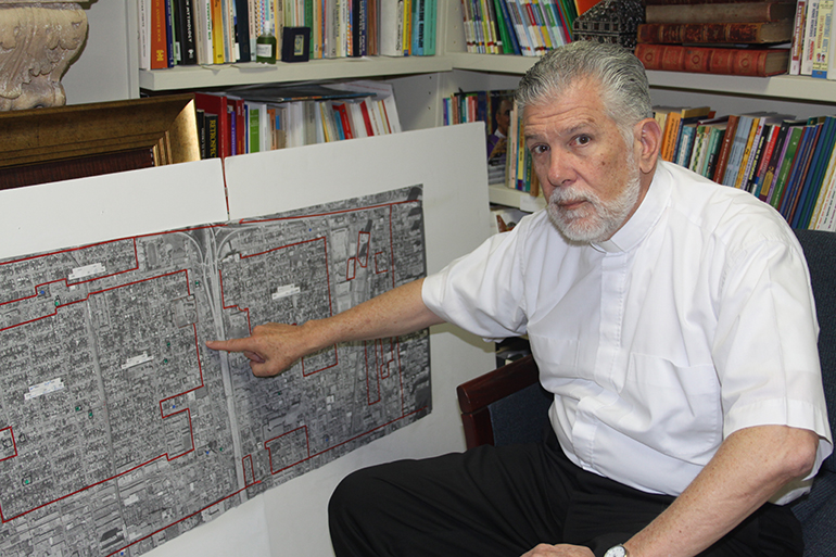 Father José Luis Menéndez, pastor of Corpus Christi points out the location of the Mother Church on the map that shows the areas in Miami encompassed by the parish.