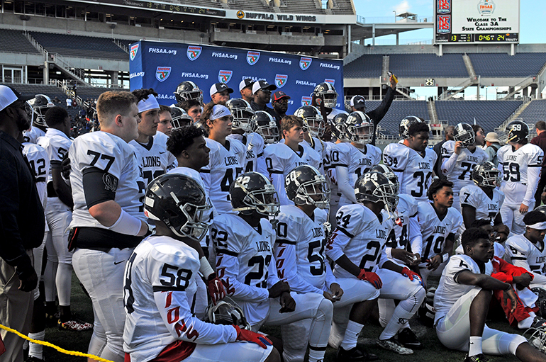 Chaminade-Madonna players and coaches pose with the state runner-up trophy after their 24-13 loss to Jacksonville Trinity Christian Dec. 10 in the Class 3A state championship game at Camping World Stadium.