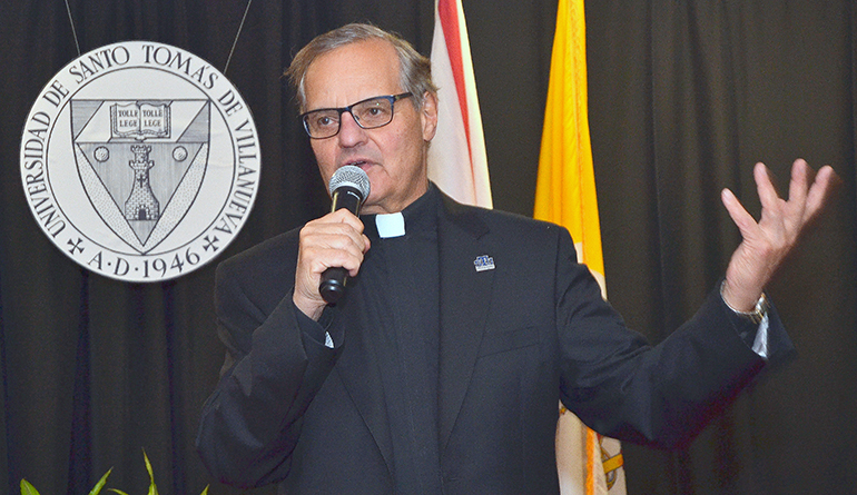 Msgr. Franklyn Casale, president of St. Thomas University, speaks in front of the original seal for the school from its birth in Havana.