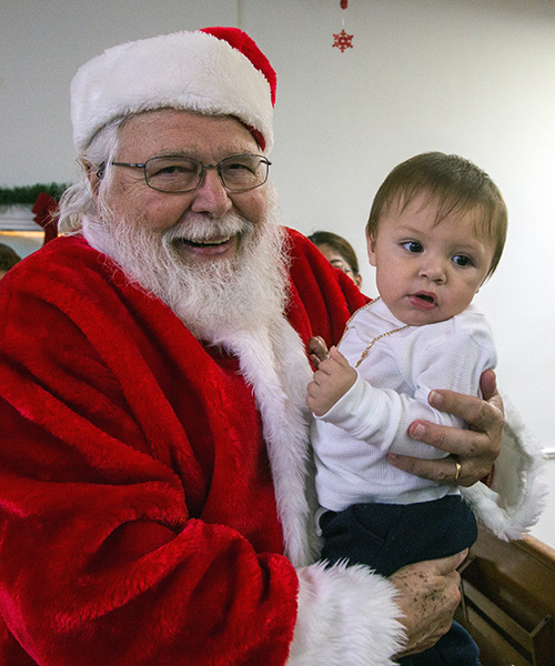 Santa Claus Victor Martell holds Kevin Pineda, 10 months old, during the Radio Paz St. Vincent de Paul Conference's toy distribution, held at Altagracia Mission in Allapatah on Three Kings weekend.