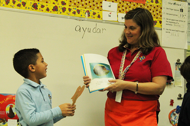 With a little help from a student, kindergarten teacher Martha Aguirre reads "La Gallinita Dorada" ("The Little Red Hen") to her class. Stories like these and others are being read in English and Spanish as part of the integration of TWIN-CS, a bilingual program launched by Boston College, into the curriculum at Holy Rosary-St. Richard School in Cutler Bay.