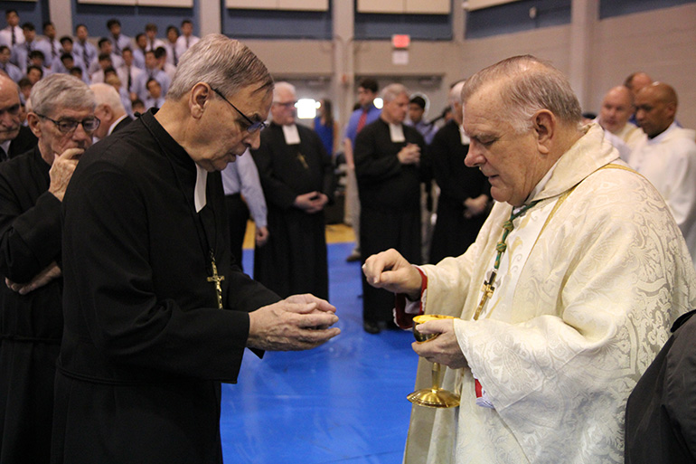 Archbishop Thomas Wenski gives Communion to one of the Marist Brothers who serve at Christopher Columbus High School. The Marist Brothers are celebrating the 200th anniversary of their foundation this year.