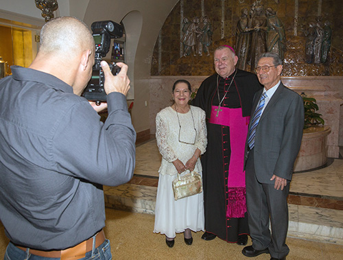 Lenier Perez of Yamila Images photographs marriage jubilarians with Archbishop Thomas Wenski before the annual wedding anniversaries Mass at St. Mary Cathedral Feb. 11, 2017.
