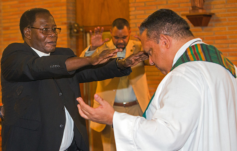 Father Alexander Ekechukwu, pastor of Holy Redeemer, left, blesses Redemptorist Father Maurice Nutt before the start of the first night of the annual black Catholic pre-Lent revival, held Feb. 12-15.