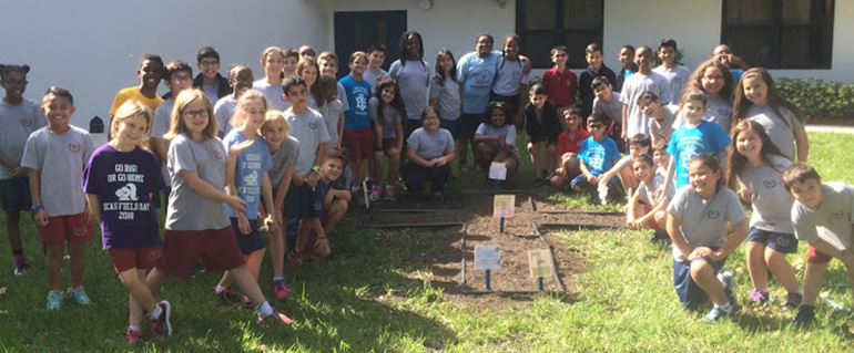 Fourth- and fifth-graders at St. Andrew School stand next to their experimental garden, where they are growing plants that could be grown in space, in order to feed astronauts on longterm space voyages.