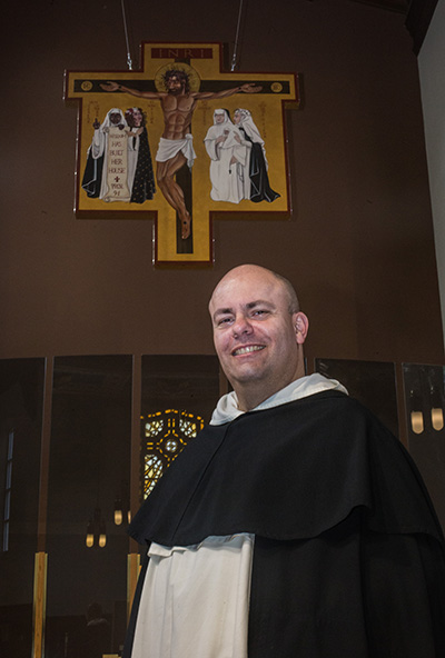 Dominican Father Cristobal Torres poses in front of the cross he designed for the newly-renovated Cor Jesu Chapel at Barry University.