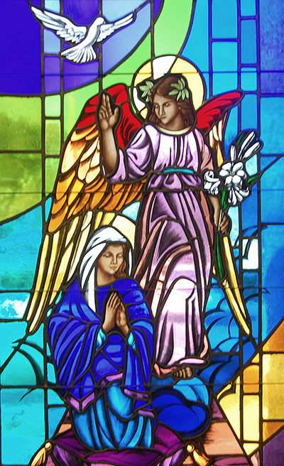 This stained glass window at St. Maximilian Kolbe Church in Pembroke Pines depicts the angel Gabriel announcing to a humble Mary that she will bear the Son of God. He holds Easter lilies, a symbol of the death and resurrection of Jesus. A hovering dove symbolizes the Holy Spirit.