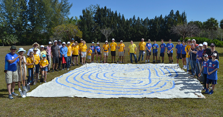 Workers line a cloth labyrinth, showing the size of the structure for which they broke ground.