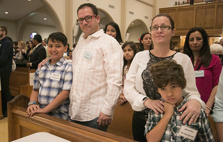 Two of the "elect," catechumens Alejandro Paez, 10, left, and his brother Gabriel, 7, of Our Lady of Lourdes Parish in Kendall, stand with their godparents, Joel Campos and Maria Buscemi, during the first of two Rite of Election ceremonies March 5 at St. Mary Cathedral.
