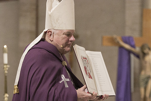Archbishop Thomas Wenski processes with one of the eight Books of the Elect that were signed during the first of two Rite of Election ceremonies March 5 at St. Mary Cathedral.