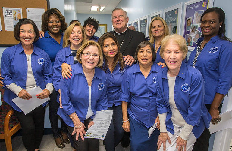 Archbishop Thomas Wenski poses for a photo with Respect Life volunteers after blessing the new offices of the relocated North Dade Pregnancy Help Center in Miami Gardens.