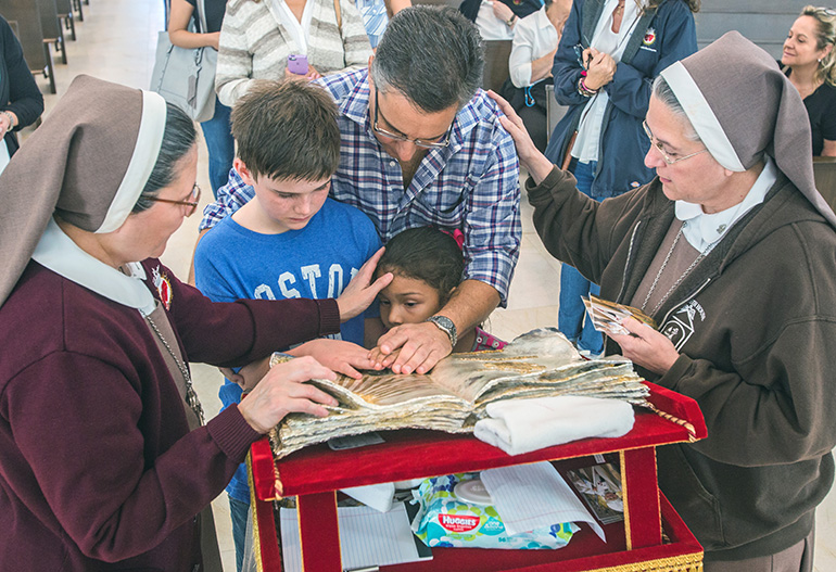 Sister Ana Margarita Lanzas, of the Servants of the Pierced Hearts of Jesus and Mary, touches the forehead of Susana Quintero, 7, as Gabriel Quintero, 9, Javier Quintero, and Mother Adela Galindo pray and touch the relic of St. John Paul II.