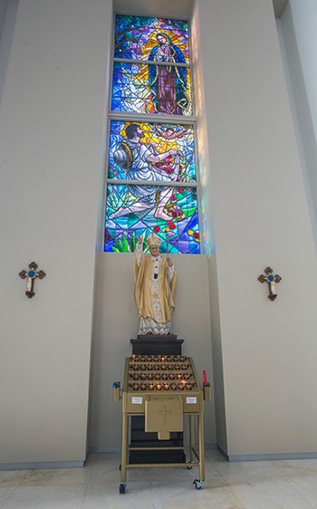 Statue of St. John Paul II at Our Lady of Guadalupe Church, located in a niche underneath a stained glass window depicting her apparition to St. Juan Diego.