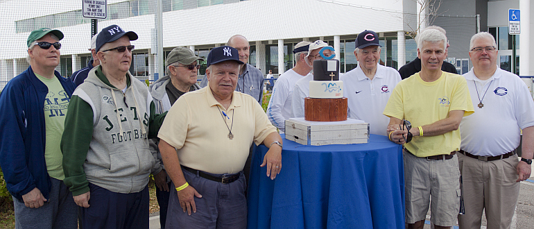 Marist Brothers in Miami gather around a three-tier cake decorated with Marist imagery at the order's 200th Anniversary Picnic at Christopher Columbus High School.