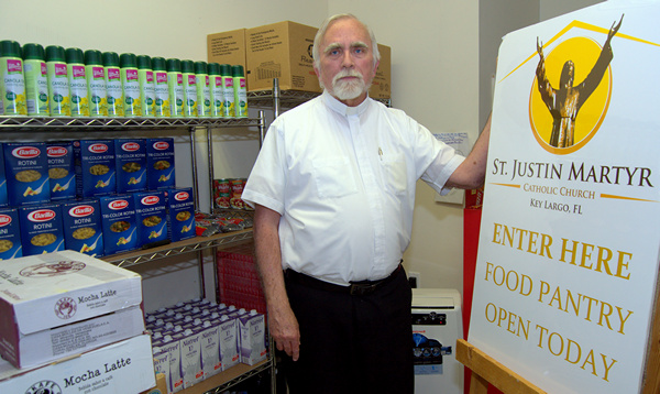 Father Stephen Hilley of St. Justin Martyr shows the sign the church puts out for the poor on Key Largo.