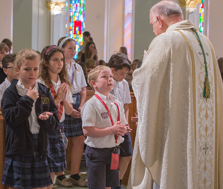 St. Anthony second grader Christopher Warner looks up at Archbishop Thomas Wenski before receiving Communion at the 90th anniversary Mass for the school, April 3 in Fort Lauderdale.