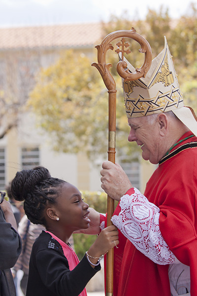 Janeska Emilien, 10, fifth grader at St. Mary's Cathedral School, holds the archbishop's crosier and receives a blessing from Archbishop Thomas Wenski at the conclusion of the Palm Sunday Mass at St. Mary Cathedral.