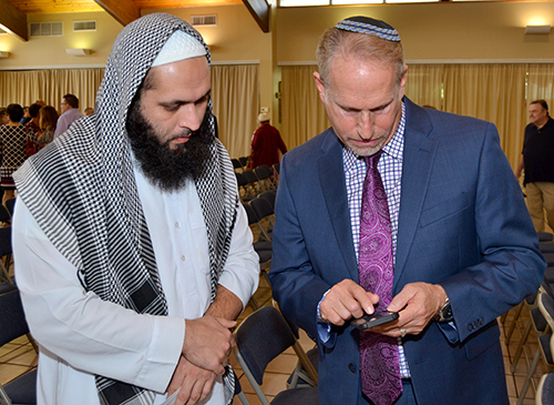 Rabbi Bradd Boxman swaps contact info with Imam Izhar Khan.