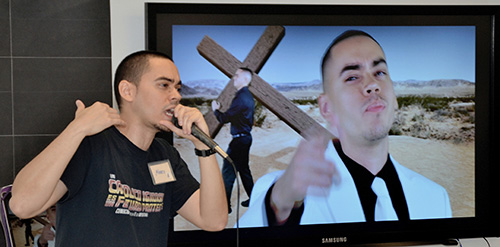Alvaro Vega does his rap number "Smile," as the video plays on a monitor.