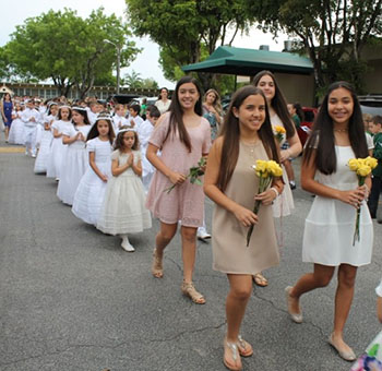 Eighth-grade students from St. Kevin School, fresh from their own confirmation, are followed by second graders still wearing their first Communion outfits as they process to the church for the May crowning.