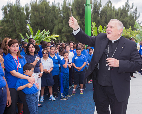 Los estudiantes y el personal del Centro Mariano observan como el Arzobispo Thomas Wenski bendice el nuevo Gimnasio y Parque Deportivo Hna. Lucia en el Centro Mariano.