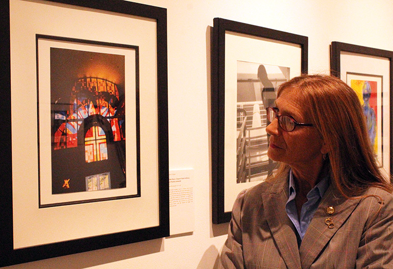 Susan Buzzi, a local photographer, victims' advocate and educator, takes a closer look at her photo "A Safe Place; Chapel of Saint Anthony, Saint Thomas University" on display at Archbishop John C. Favalora Archive and Museum at St. Thomas University. Her exhibit, "Responsibility and Vigilance," is a visual essay that examines domestic servitude, forced labor and human trafficking in the U.S.