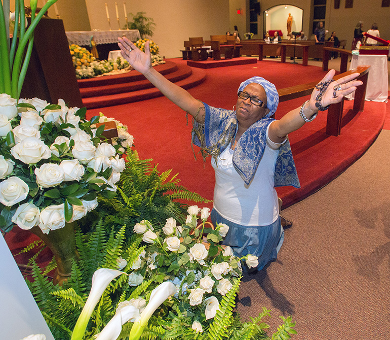 Haitian-American Angel Thomas prays before the statue of Our Lady of Fatima inside St. Michael Church.