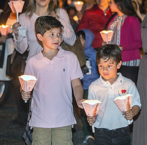 Max Gabaldon, 8, and Gabriel Echevarria, 6, carry candles in the procession around the grounds of St. Michael the Archangel Church in Miami.