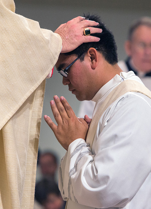 By the laying on of hands, Archbishop Thomas Wenski ordains Father James Arriola.