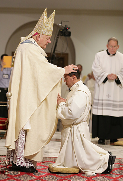 El Arzobispo Thomas Wenski le impone las manos a Luis Flores, ordenándolo al sacerdocio.