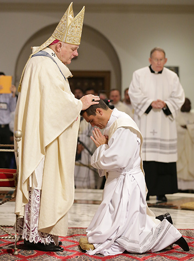 Archbishop Thomas Wenski lays hands on Juan Carlos Salazar, ordaining him to the archdiocesan priesthood.