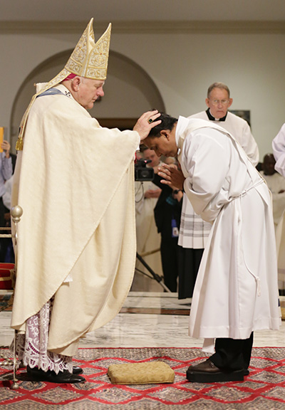 Archbishop Thomas Wenski lays hands on Mathew Padickal Thomas, ordaining him to the archdiocesan priesthood.