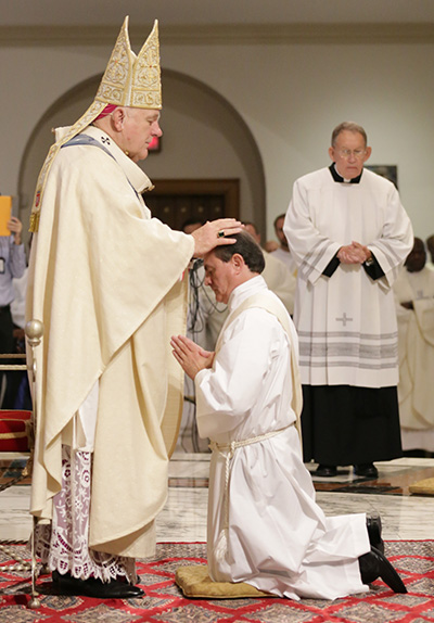 Archbishop Thomas Wenski lays hands on Oswaldo Agudelo, ordaining him to the archdiocesan priesthood.