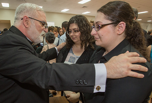 El recién ordenado P. Joseph Maalouf bendice a sus hijas, Mary Maalouf, a la izquierda, y Angie Maalouf, después de la Misa.