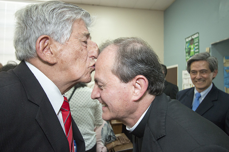 Gabriel de Jesús Agudelo besa la frente de su hijo recién ordenado, el P. Oswaldo Agudelo, después de la ceremonia de ordenación. Mirando a la derecha está su hermano mayor, Gabriel, quien será ordenado sacerdote para la Diócesis de Brooklyn, el próximo año.