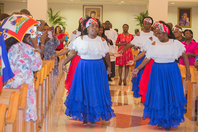 Members of St. James Church's Fraternite dance group lead the procession into Notre Dame d'Haiti Church for the Haitian Flag Day celebration May 18.