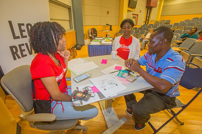 Cassandra Suprin, supervising attorney for Catholic Legal Services, and Tanya Dwyer, attorney, help Paul Pierre with his citizenship application during the New Americans Campaign citizenship clinic at Miami Dade College North Campus May 20.