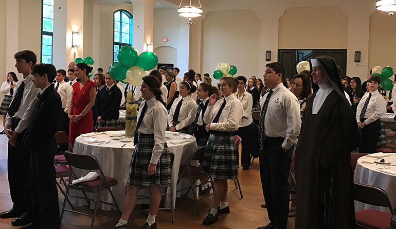 Students, teachers and alumni sing the St. Theresa School anthem at the start of the induction luncheon.