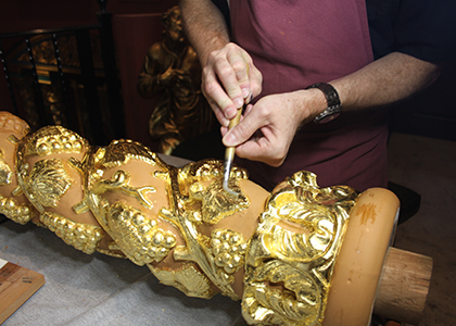 Ulises Acosta shows how the gold foil is placed on a column of carved cedar wood. Acosta is one of the three specialists who are placing the gold leaf on the altars of the La Merced Church-Museum, located at Corpus Christi Church in Miami.