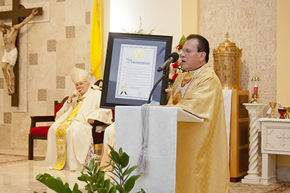 Father Alvaro Huertas, administrator of Santa Barbara Church, holds a City of Hialeah Gardens proclamation commemorating his parish's 30th anniversary. The proclamation was given to the church by Manuel Carrera, Emergency Management Coordinator for the city.