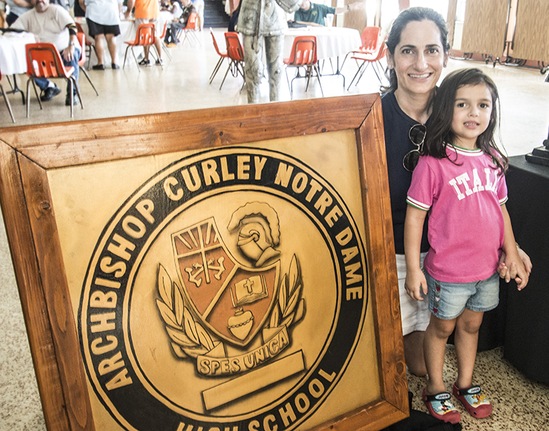 Selena Samios Smith, a 1990 graduate, poses with the Archbishop Curley-Notre Dame seal and her daughter, Marya Smith.