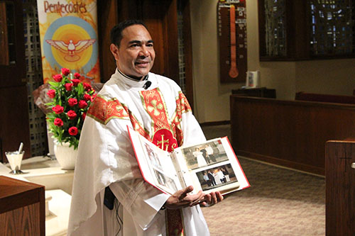 Father Wilfredo Contreras shows a photo album filled with pictures of all of the couples at whose weddings he has presided, and for whom he prays. Father Contreras has married couples from St. John Bosco Church, St. Brendan Church, St. Brendan Church, St. Clement Church, St. Patrick Church and St. Martha Church.