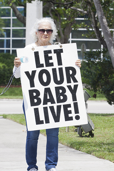 Santa Casagrande, a parishioner at Nativity Church in Hollywood, holds up a sign during the "Jericho Walk."