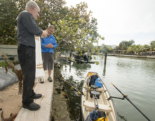 Father Roberto Cid, pastor of St. Patrick Church, Miami Beach, blesses Greg Dougherty and the craft on which he is embarking on a 1,400-mile sea journey from Miami to New York. Dougherty's journey aims to show his dedication to Our Lady of Fatima, and to inspire children and families who do not have a relationship with the Blessed Mother to begin praying the rosary.