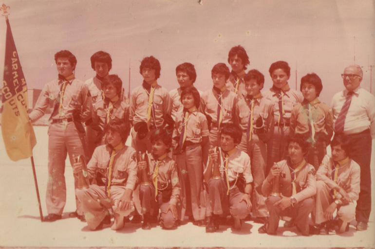 Al crecer en Malta, el obispo auxiliar Peter Baldacchino (el que sostiene la bandera) estaba activo en los exploradores. Esta foto fue incluida en el folleto del programa para que los niños pudieran verlo y al final de la Misa, el Obispo llamó su atención a las fotos
y les recordó que cuando él se encontraba allá, estaba seguro de que nunca sería un sacerdote. Sin embargo, Dios tenía planes para él, y él escuchó y respondió.