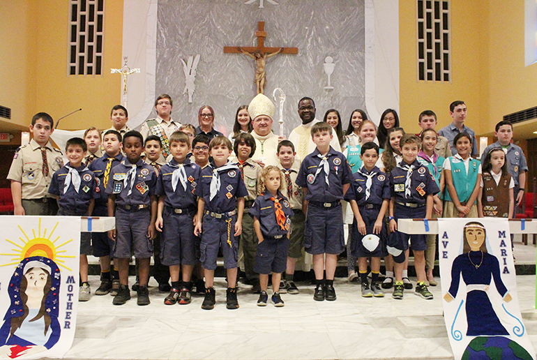 El Obispo Auxiliar Peter Baldacchino y Mons. Chanel Jeanty, Canciller de Asuntos Canónicos y Vicario General, posan junto a niños exploradores de la Arquidiócesis de Miami con motivo de una Misa conmemorativa en la parroquia St. James, el 10 de junio.