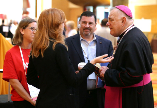 Archbishop Wenski talks with people at the Convocation of Catholic Leaders in Orlando. In the center is Stephen Colella, archdiocesan secretary of parish life.